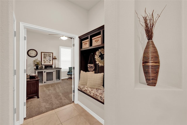 hall featuring light carpet, baseboards, and light tile patterned floors