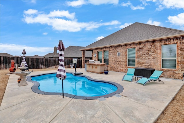 view of pool featuring exterior kitchen, a patio area, and fence