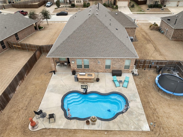 view of pool with a trampoline, a patio area, and a fenced backyard