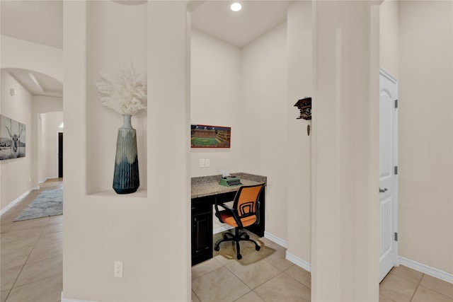 office space with light tile patterned floors, arched walkways, recessed lighting, baseboards, and built in study area