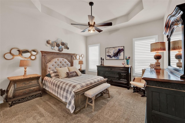 bedroom featuring light carpet, a raised ceiling, and a ceiling fan