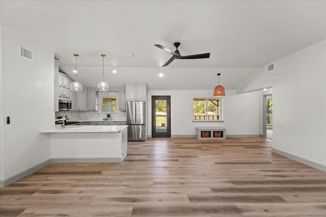 kitchen featuring white cabinetry, kitchen peninsula, stainless steel appliances, vaulted ceiling, and pendant lighting