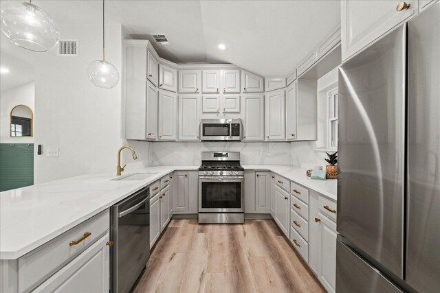 kitchen with appliances with stainless steel finishes, sink, pendant lighting, and tasteful backsplash