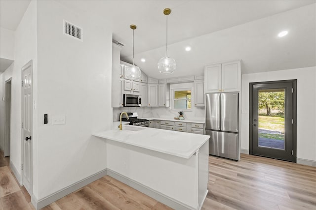 kitchen with appliances with stainless steel finishes, light hardwood / wood-style flooring, decorative light fixtures, white cabinetry, and kitchen peninsula