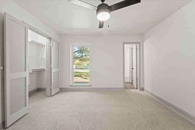 unfurnished bedroom with light colored carpet, ensuite bath, a closet, ceiling fan, and a spacious closet