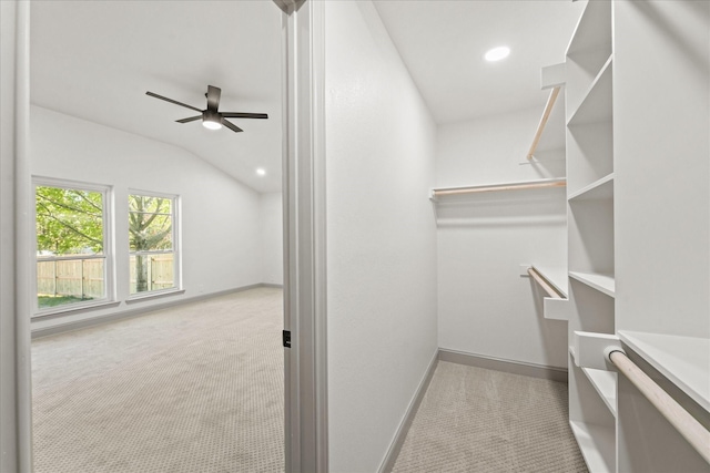 walk in closet featuring light carpet, vaulted ceiling, and ceiling fan