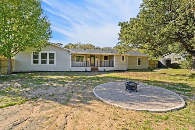 rear view of property featuring an outdoor fire pit and a porch