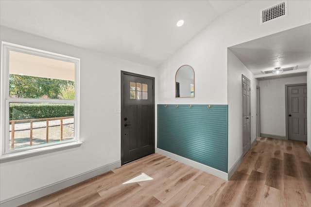 foyer entrance with hardwood / wood-style flooring, vaulted ceiling, and a healthy amount of sunlight