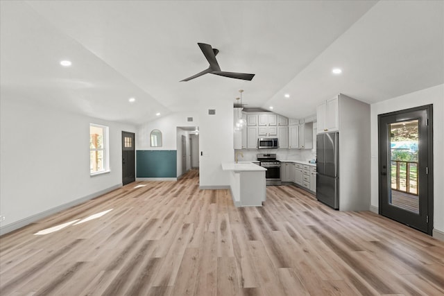 kitchen with hanging light fixtures, stainless steel appliances, vaulted ceiling, a wealth of natural light, and white cabinetry