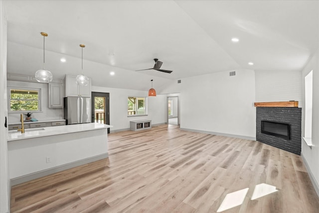 unfurnished living room featuring light hardwood / wood-style floors, vaulted ceiling, and sink