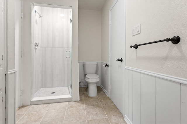 bathroom with a tile shower, tile patterned flooring, and toilet