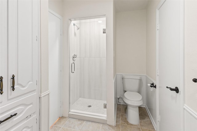 bathroom featuring a shower with door, toilet, and tile patterned floors