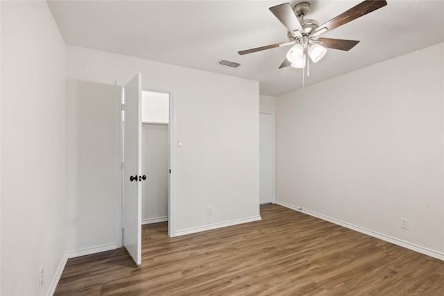 unfurnished bedroom featuring ceiling fan, a spacious closet, dark hardwood / wood-style flooring, and a closet