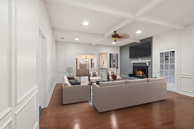 living room featuring a brick fireplace, coffered ceiling, dark hardwood / wood-style flooring, and beam ceiling