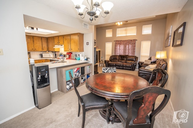 carpeted dining area featuring sink, an inviting chandelier, and a textured ceiling