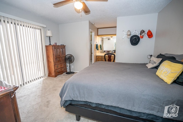 carpeted bedroom with ensuite bath, ceiling fan, and a textured ceiling