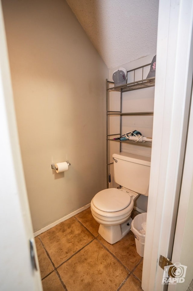 bathroom featuring tile patterned floors, a textured ceiling, vaulted ceiling, and toilet