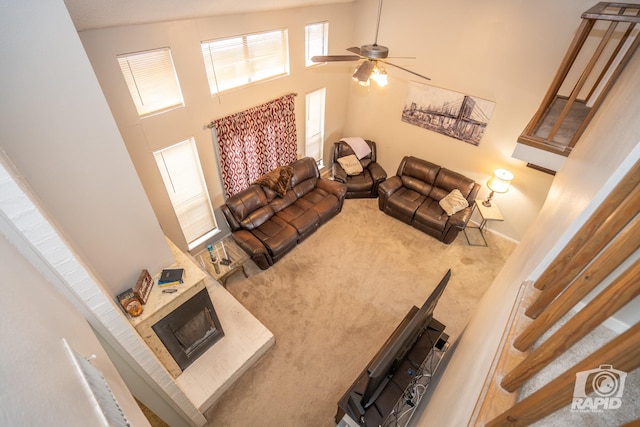 living room with ceiling fan, carpet floors, and a high ceiling