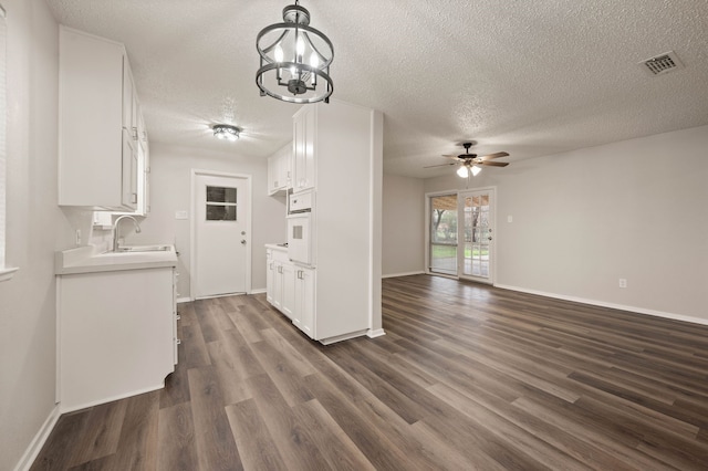 kitchen featuring white oven, light countertops, visible vents, white cabinets, and a sink