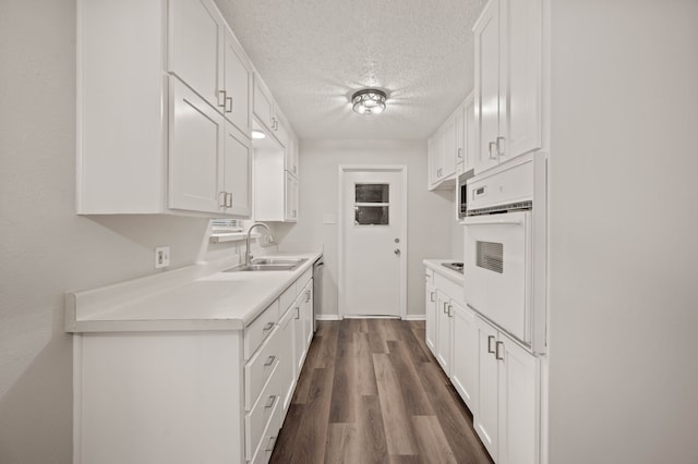 kitchen with a sink, white cabinetry, light countertops, stainless steel dishwasher, and white oven