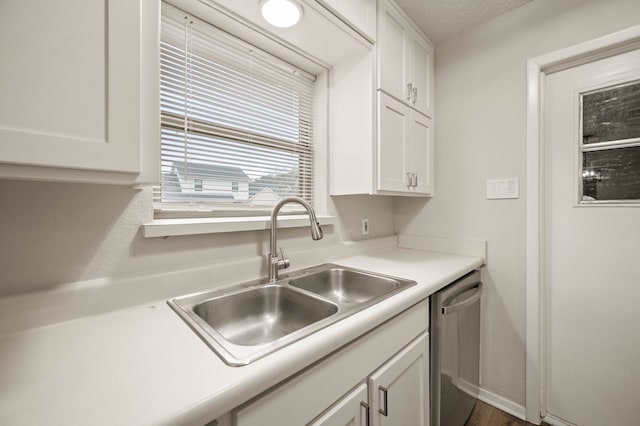 kitchen with white cabinets, light countertops, a sink, and stainless steel dishwasher