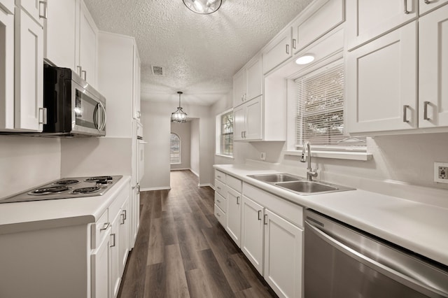 kitchen with light countertops, appliances with stainless steel finishes, a sink, and white cabinetry