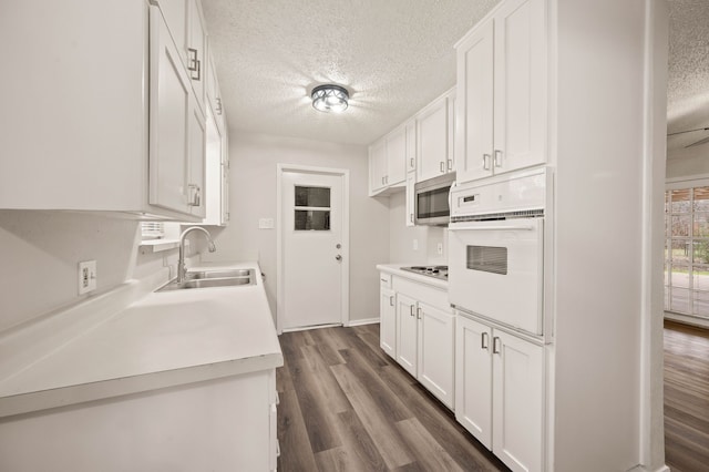 kitchen featuring white oven, light countertops, stainless steel microwave, white cabinets, and a sink