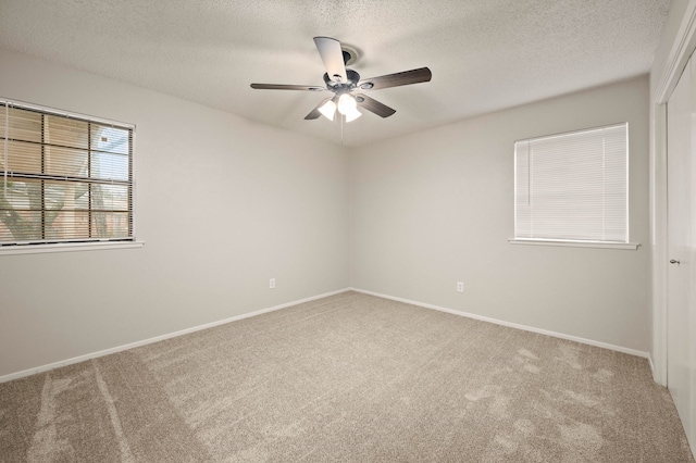 empty room with carpet, a ceiling fan, and baseboards