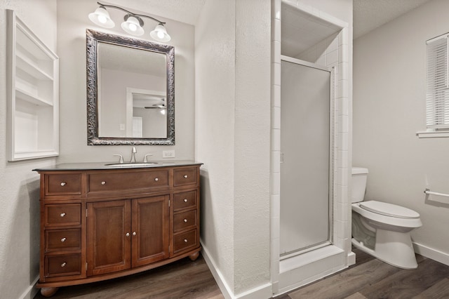 full bath with vanity, a stall shower, wood finished floors, and toilet