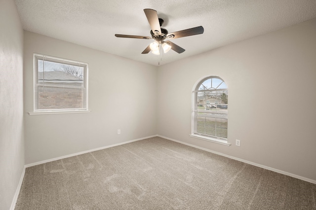 empty room featuring ceiling fan, a textured ceiling, baseboards, and carpet flooring