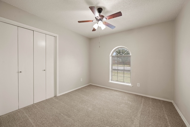 unfurnished bedroom featuring a textured ceiling, ceiling fan, carpet flooring, baseboards, and a closet