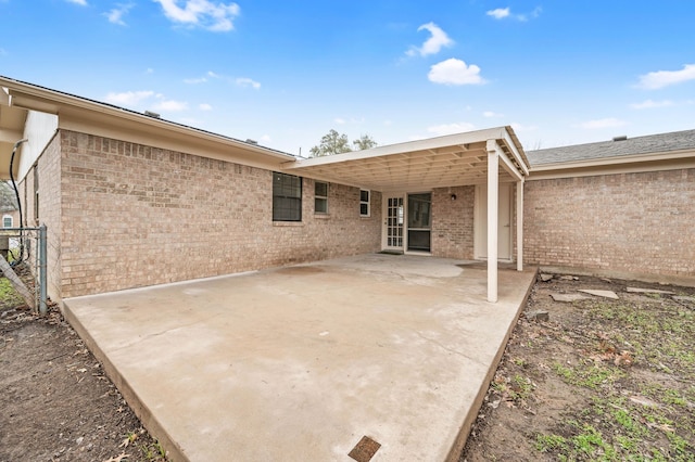 back of house featuring brick siding and a patio