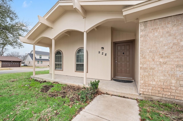 doorway to property with a porch and brick siding