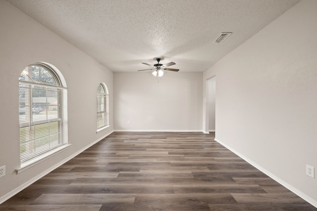 spare room with baseboards, dark wood-type flooring, visible vents, and a ceiling fan