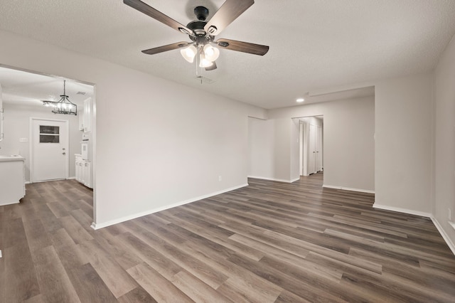 unfurnished room with dark wood-style floors, a textured ceiling, baseboards, and ceiling fan with notable chandelier