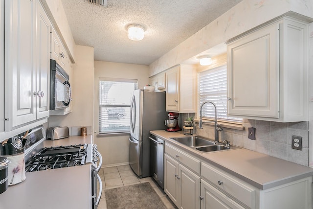 kitchen with white cabinets, plenty of natural light, stainless steel appliances, and sink