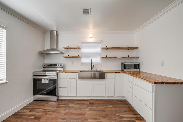 kitchen with stainless steel appliances, sink, white cabinets, wood counters, and wall chimney range hood