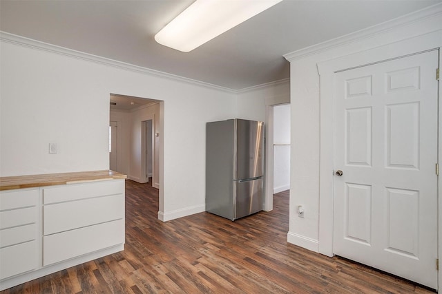 kitchen featuring dark hardwood / wood-style flooring, ornamental molding, white cabinetry, and stainless steel fridge