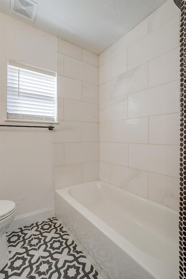 bathroom with tiled shower / bath combo and toilet