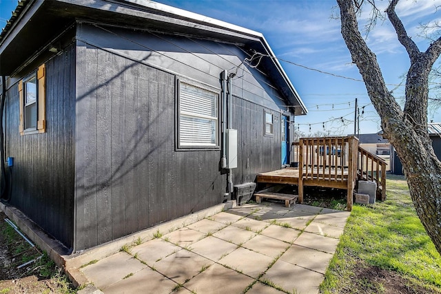 view of property exterior featuring a wooden deck and a patio area