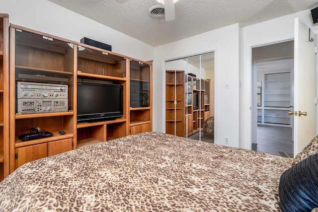 bedroom featuring ceiling fan, a textured ceiling, a closet, and hardwood / wood-style floors