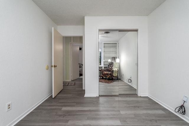 hallway with a textured ceiling and hardwood / wood-style floors