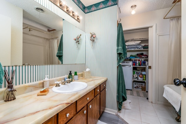 bathroom featuring tile patterned floors, vanity, washer / clothes dryer, and a textured ceiling