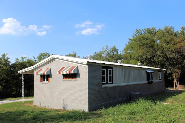 view of home's exterior with brick siding, a yard, and central AC unit