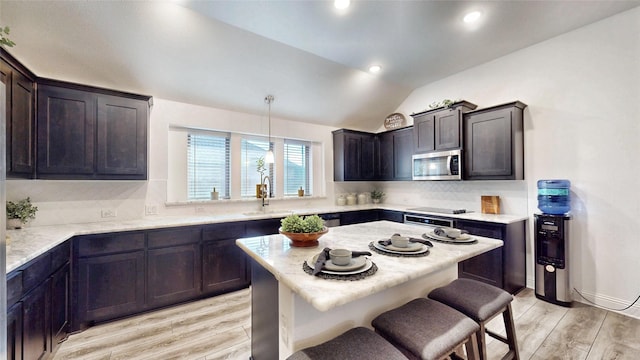 kitchen featuring decorative light fixtures, dark brown cabinets, backsplash, and light hardwood / wood-style flooring