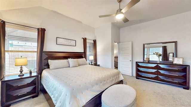 bedroom with multiple windows, vaulted ceiling, ceiling fan, and light colored carpet