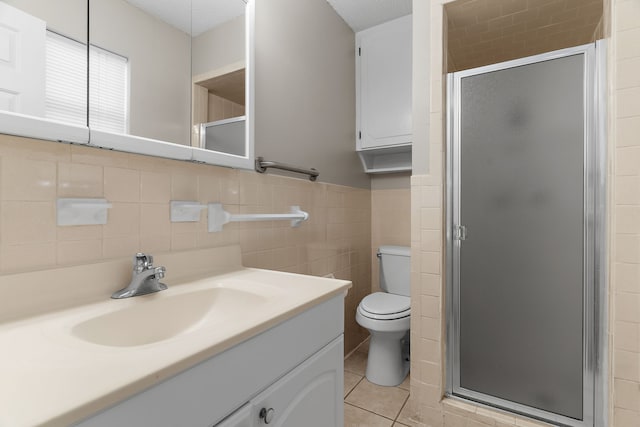 bathroom featuring tile walls, vanity, a shower with door, and tile patterned floors