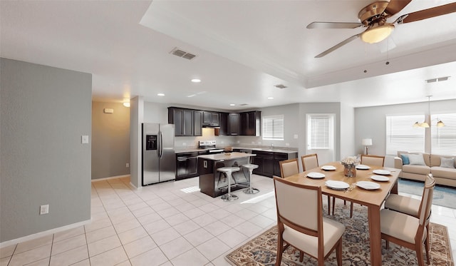 dining space featuring light tile patterned floors, a tray ceiling, visible vents, and a ceiling fan