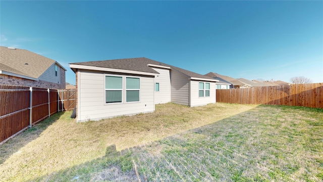 rear view of house with a yard, a shingled roof, and a fenced backyard