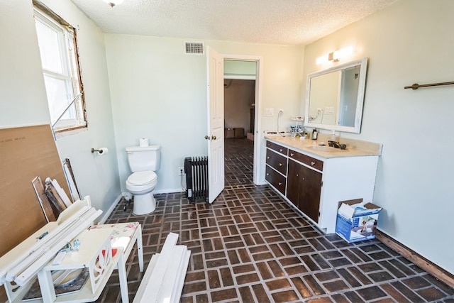 bathroom featuring radiator heating unit, a textured ceiling, vanity, and toilet